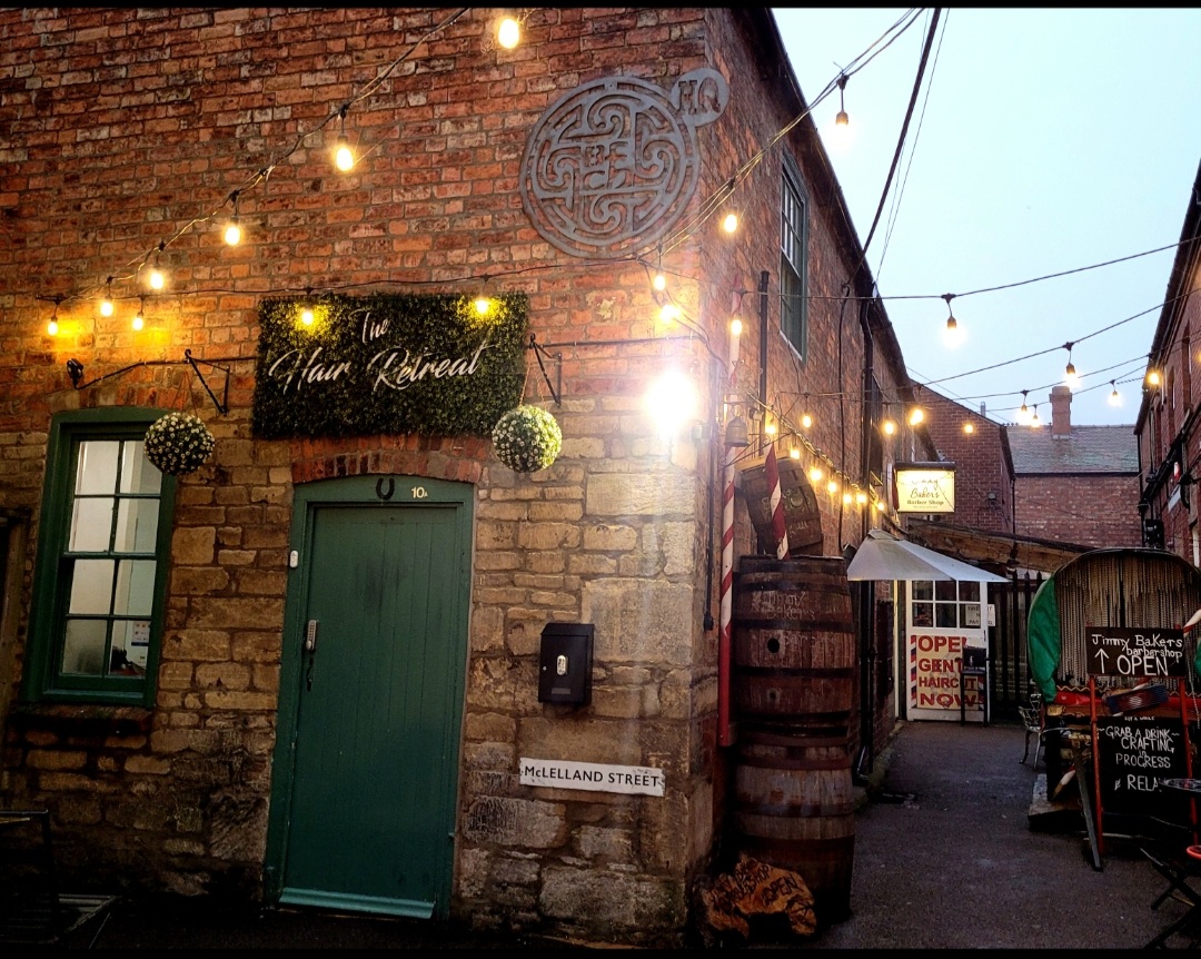 The old courtyard at dusk with festoon lights and a green door