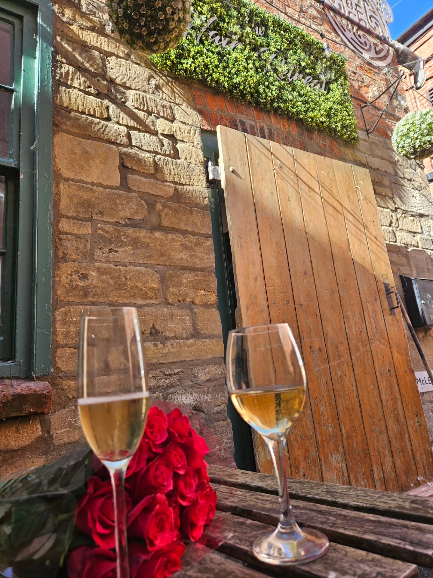 Two glasses of fizz and red roses outside the door of the old salon